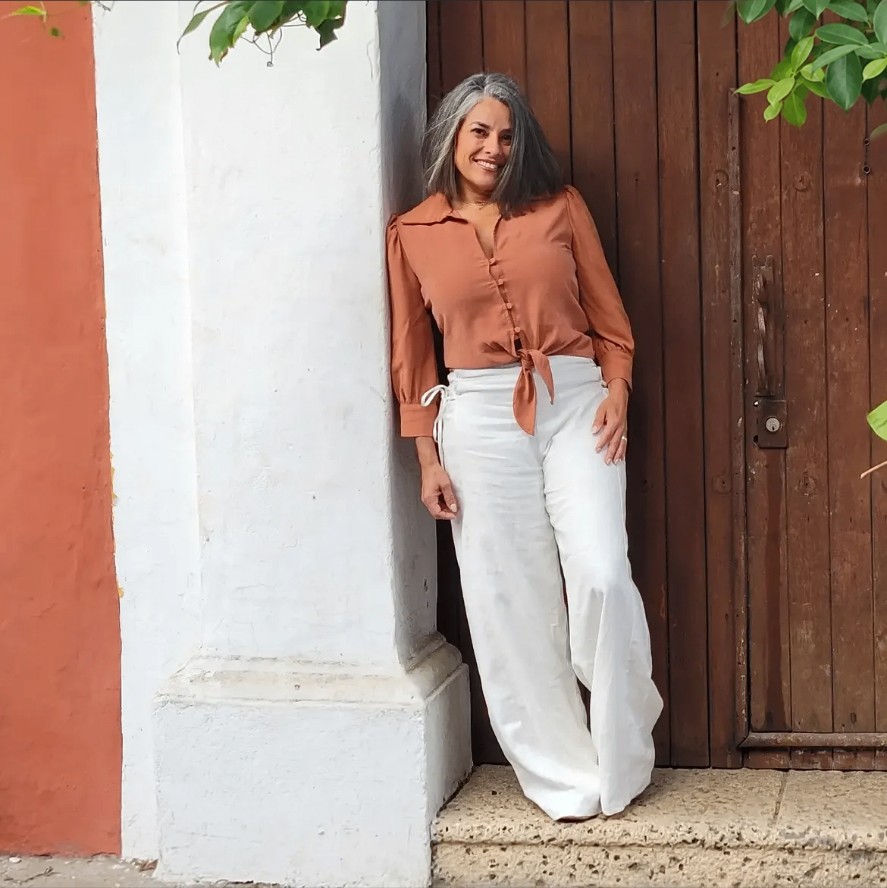 Marisol in a terracotta blouse leaning against a pillar in Cartagena